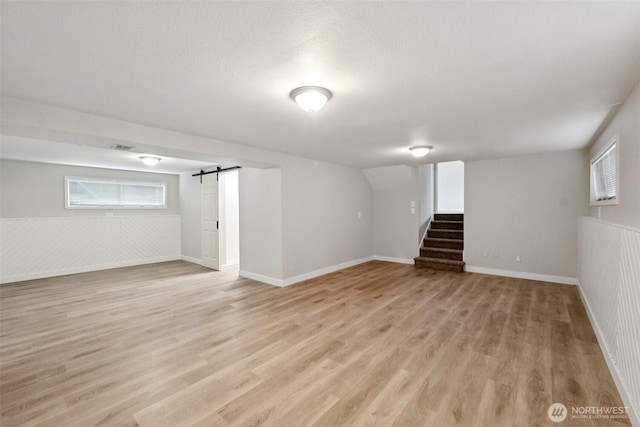9442 S K St, Tacoma, WA 98444 - below grade area featuring stairway, light wood-style floors, healthy amount of natural light, a barn door, and a wainscoted wall