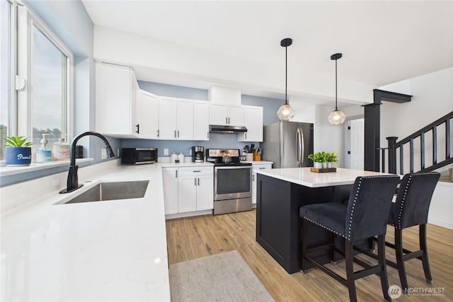 612 Dune Crest Loop, Westport, WA 98595 - kitchen with stainless steel appliances, under cabinet range hood, a breakfast bar area, a center island, and white cabinets