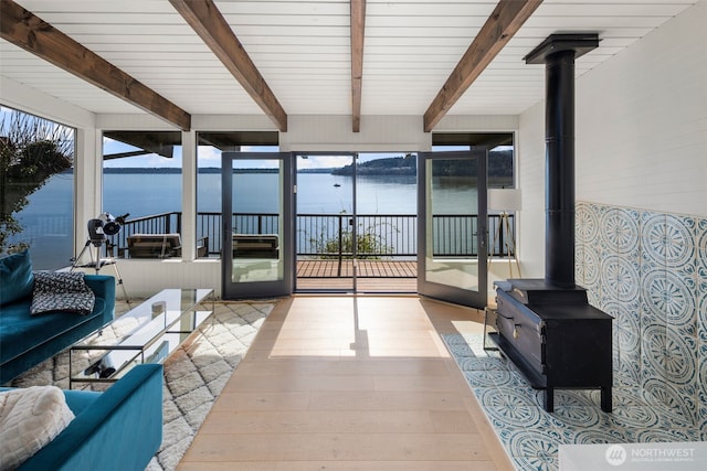 28605 Manzanita Beach Rd SW, Vashon, WA 98070 - sunroom / solarium with a water view, a wood stove, beamed ceiling, and plenty of natural light