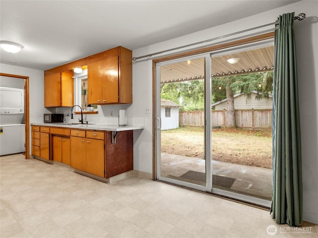 10818 108th St SW, Lakewood, WA 98498 - kitchen featuring stacked washing machine and dryer, light countertops, light floors, and brown cabinetry