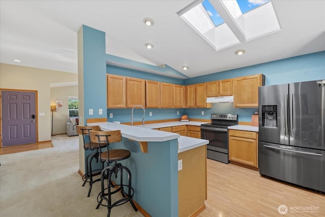 2420 Forest Ridge Dr SE, Auburn, WA 98002 - kitchen with stainless steel appliances, under cabinet range hood, a skylight, light countertops, and a breakfast bar
