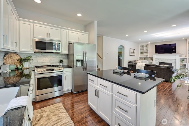 3606 Tree Farm Ct, Bellingham, WA 98226 - kitchen with stainless steel appliances, dark countertops, arched walkways, white cabinetry, and dark wood finished floors
