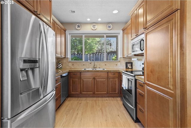 126 28th St NW, Long Beach, WA 98631 - kitchen with stainless steel appliances, light wood finished floors, backsplash, brown cabinets, and recessed lighting