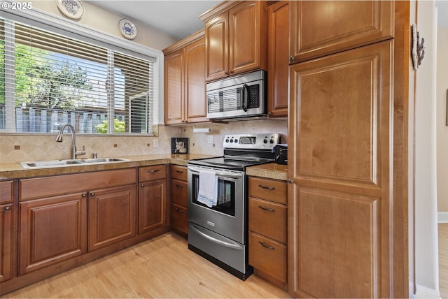 126 28th St NW, Long Beach, WA 98631 - kitchen featuring stainless steel appliances, light wood-style floors, decorative backsplash, and brown cabinets