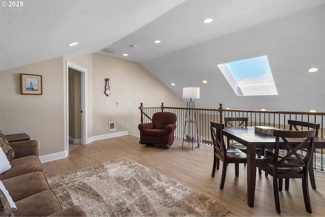 126 28th St NW, Long Beach, WA 98631 - dining room featuring a skylight, vaulted ceiling, light wood finished floors, and a textured ceiling