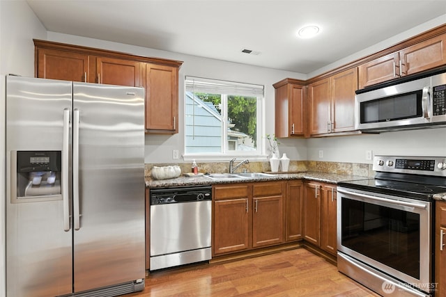 7436 S G St, Tacoma, WA 98408 - kitchen with appliances with stainless steel finishes, light wood-style flooring, brown cabinets, and stone countertops