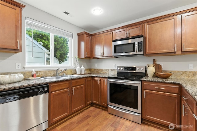 7436 S G St, Tacoma, WA 98408 - kitchen with appliances with stainless steel finishes, light wood finished floors, brown cabinets, and stone countertops
