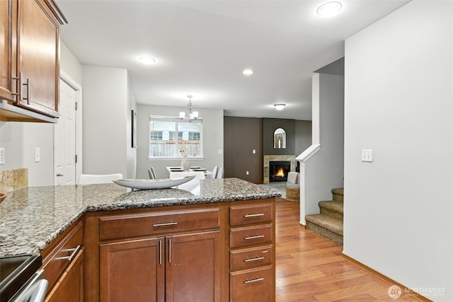 7436 S G St, Tacoma, WA 98408 - kitchen with a peninsula, light wood-style flooring, a glass covered fireplace, stainless steel stove, and brown cabinets