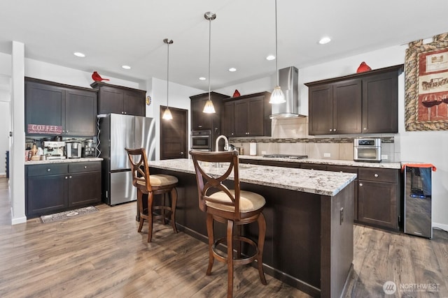 4831 Skylark St NE, Olympia, WA 98516 - kitchen featuring appliances with stainless steel finishes, wall chimney exhaust hood, dark brown cabinetry, tasteful backsplash, and recessed lighting