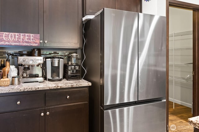 4831 Skylark St NE, Olympia, WA 98516 - kitchen with freestanding refrigerator, dark brown cabinets, wood finished floors, light stone countertops, and tasteful backsplash