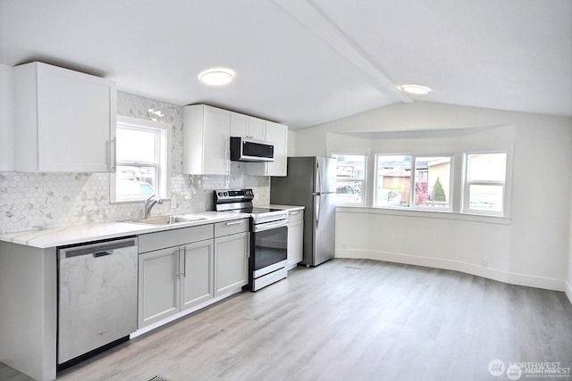 210 37th St SE Unit 35, Auburn, WA 98002 - kitchen featuring appliances with stainless steel finishes, vaulted ceiling, decorative backsplash, light countertops, and light wood-style flooring