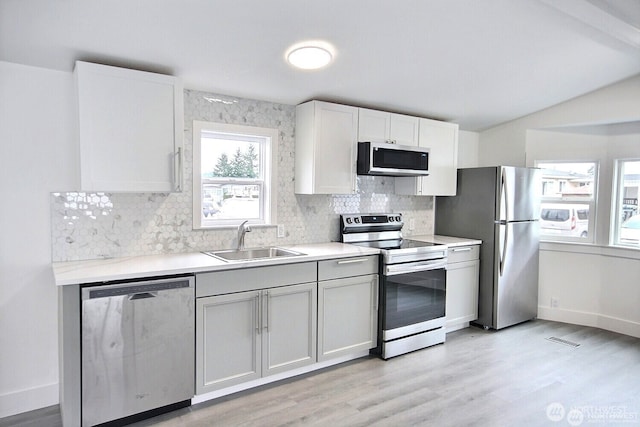 210 37th St SE Unit 35, Auburn, WA 98002 - kitchen with stainless steel appliances, decorative backsplash, light wood finished floors, light countertops, and vaulted ceiling