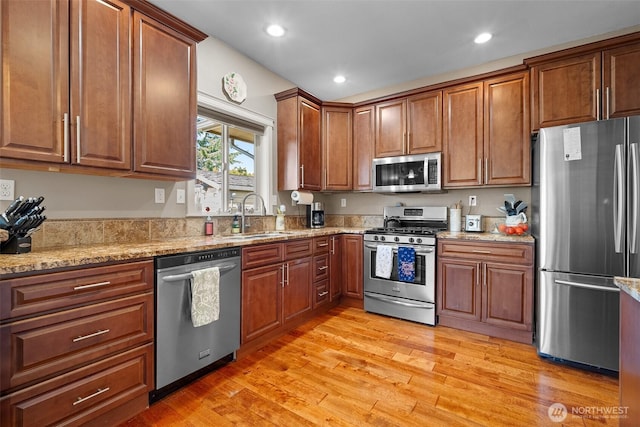 1918 Tundra Loop, Mount Vernon, WA 98273 - kitchen with stainless steel appliances, light stone counters, recessed lighting, light wood-style flooring, and brown cabinets