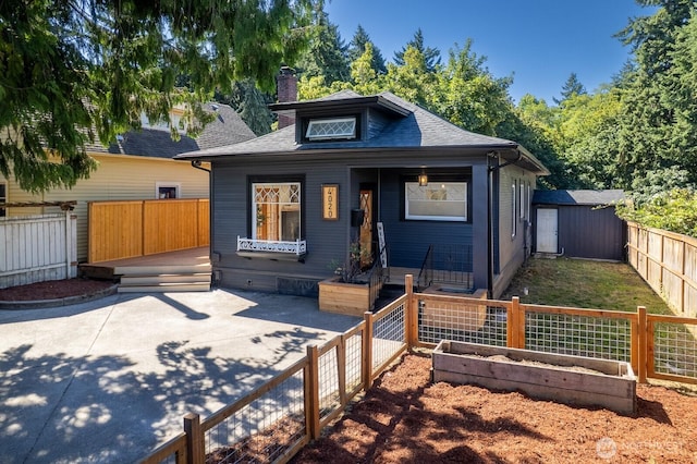 4020 N 34th St, Tacoma, WA 98407 - bungalow-style home featuring a garden, a chimney, roof with shingles, a fenced backyard, and a patio area