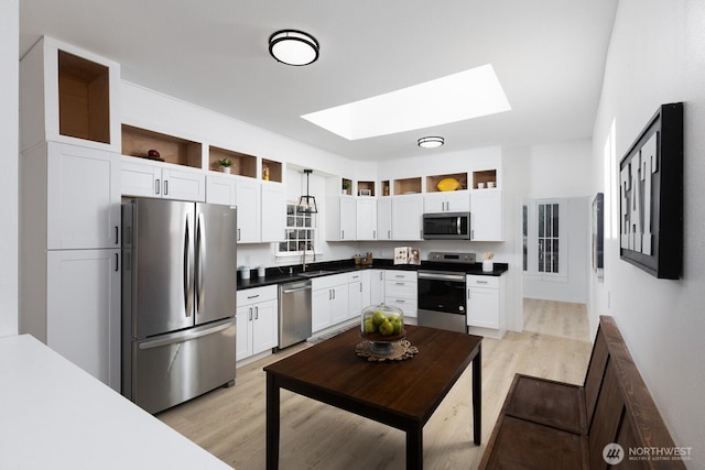 4020 N 34th St, Tacoma, WA 98407 - kitchen with stainless steel appliances, a skylight, light wood-style floors, white cabinetry, and dark countertops