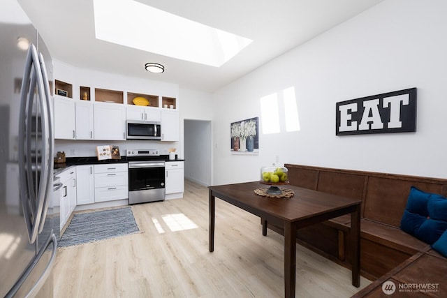 4020 N 34th St, Tacoma, WA 98407 - kitchen featuring a skylight, appliances with stainless steel finishes, white cabinetry, dark countertops, and light wood-style flooring