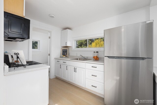 4020 N 34th St, Tacoma, WA 98407 - kitchen with freestanding refrigerator, light countertops, light wood finished floors, white cabinetry, and stove