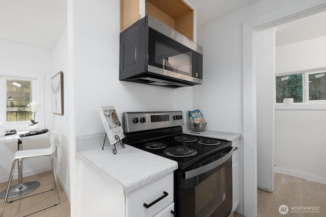 4020 N 34th St, Tacoma, WA 98407 - kitchen featuring electric range, stainless steel microwave, light wood-type flooring, and white cabinetry