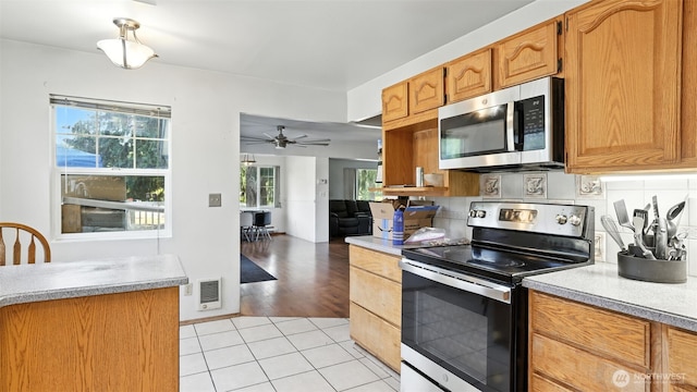 32626 46th Pl S, Auburn, WA 98001 - kitchen featuring appliances with stainless steel finishes, light countertops, light tile patterned floors, ceiling fan, and brown cabinetry