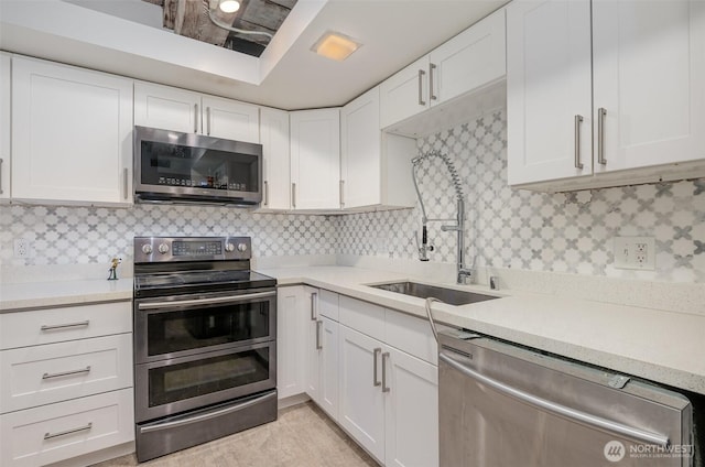 1507 Western Ave Unit R203, Seattle, WA 98101 - kitchen featuring appliances with stainless steel finishes, light countertops, white cabinetry, and backsplash