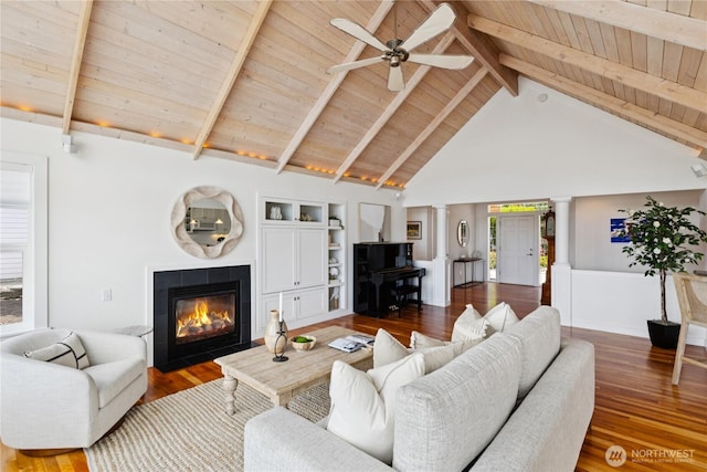 882 Shoshone Dr, La Conner, WA 98257 - living room with ornate columns, a wooden ceiling with exposed beams, a tiled fireplace, a ceiling fan, and wood finished floors