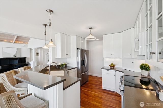 882 Shoshone Dr, La Conner, WA 98257 - kitchen featuring white appliances, decorative columns, dark countertops, a kitchen bar, and dark wood-type flooring