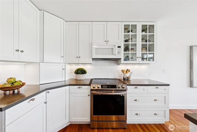 882 Shoshone Dr, La Conner, WA 98257 - kitchen with white microwave, stainless steel electric stove, dark countertops, backsplash, and white cabinetry