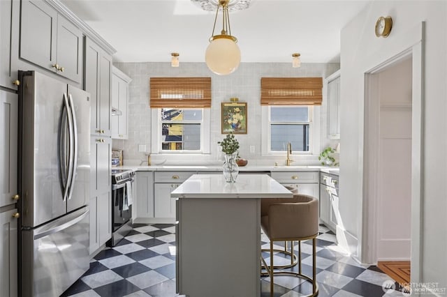 2233 2nd Ave W, Seattle, WA 98119 - kitchen with appliances with stainless steel finishes, dark flooring, a kitchen island, a breakfast bar, and gray cabinetry