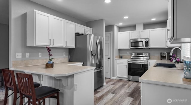 16223 Birkland St SE, Yelm, WA 98597 - kitchen with appliances with stainless steel finishes, a peninsula, white cabinets, recessed lighting, and a kitchen breakfast bar
