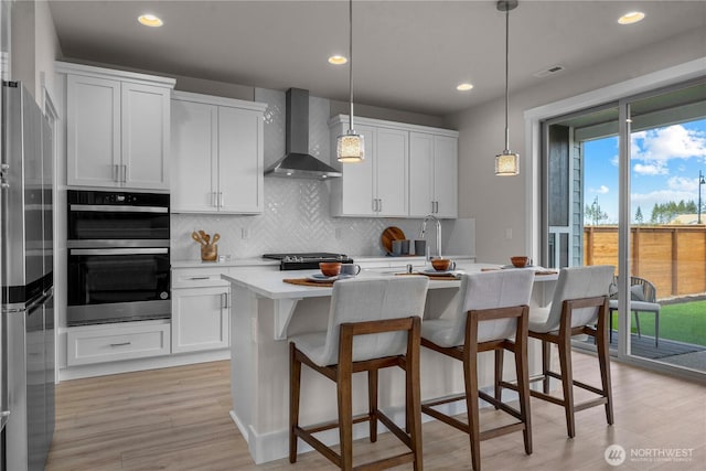 20625 153rd St E, Bonney Lake, WA 98391 - kitchen with wall chimney range hood, stainless steel appliances, light countertops, tasteful backsplash, and a kitchen bar