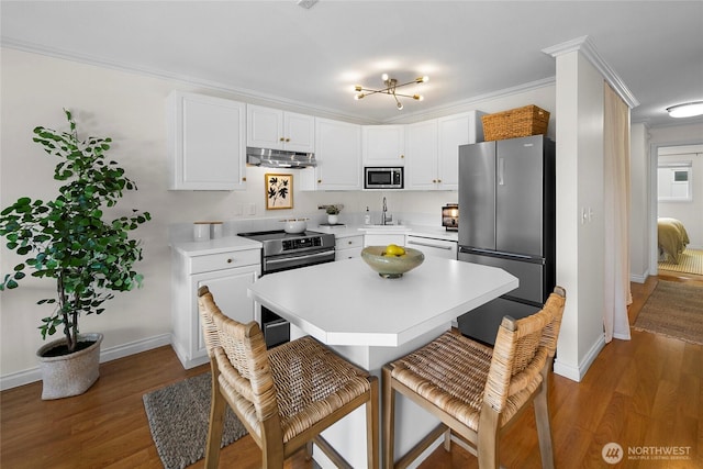 2501 Canterbury Ln E Unit 221, Seattle, WA 98112 - kitchen featuring stainless steel appliances, under cabinet range hood, a breakfast bar, light countertops, and light wood-type flooring