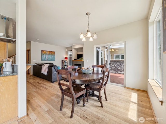 11403 SE 171st St, Renton, WA 98055 - dining room featuring light wood-style flooring, a chandelier, and a lit fireplace