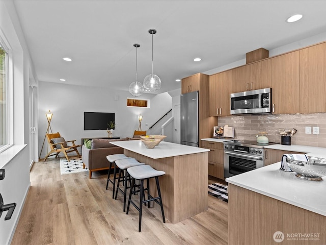 9015 Dibble Ave NW Unit B, Seattle, WA 98117 - kitchen featuring appliances with stainless steel finishes, a kitchen bar, decorative backsplash, light countertops, and recessed lighting