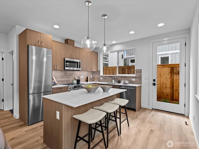 9015 Dibble Ave NW Unit B, Seattle, WA 98117 - kitchen with stainless steel appliances, a breakfast bar, light wood finished floors, backsplash, and a kitchen island