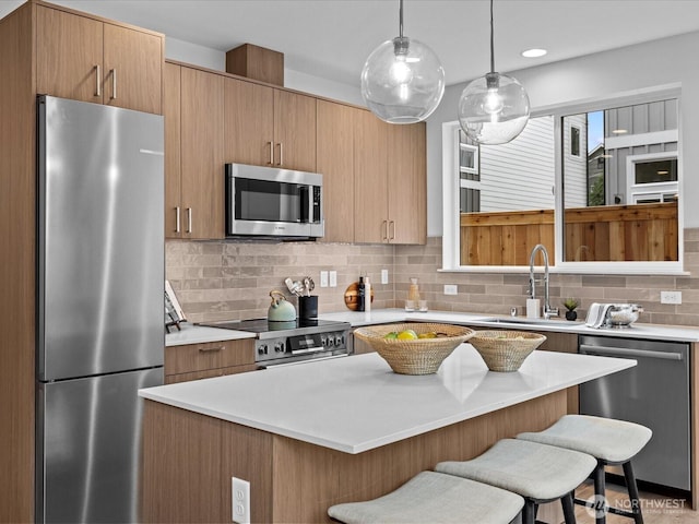 9015 Dibble Ave NW Unit B, Seattle, WA 98117 - kitchen with stainless steel appliances, a kitchen breakfast bar, light countertops, backsplash, and pendant lighting