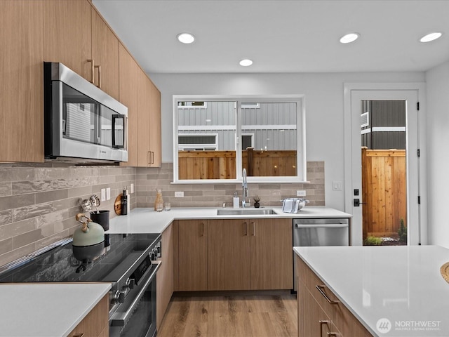 9015 Dibble Ave NW Unit B, Seattle, WA 98117 - kitchen with stainless steel appliances, tasteful backsplash, light countertops, light wood-style floors, and recessed lighting