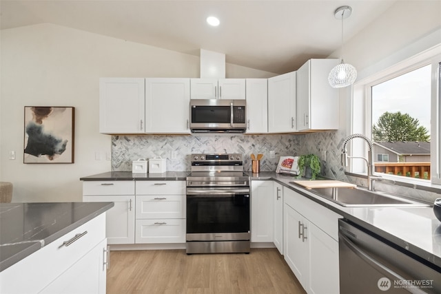 24405 24th Ave S, Des Moines, WA 98198 - kitchen with stainless steel appliances, vaulted ceiling, white cabinets, tasteful backsplash, and decorative light fixtures