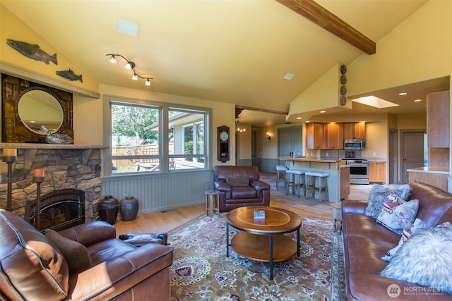 822 E Oak St, Sequim, WA 98382 - living area with light wood finished floors, a wainscoted wall, beam ceiling, a fireplace, and high vaulted ceiling