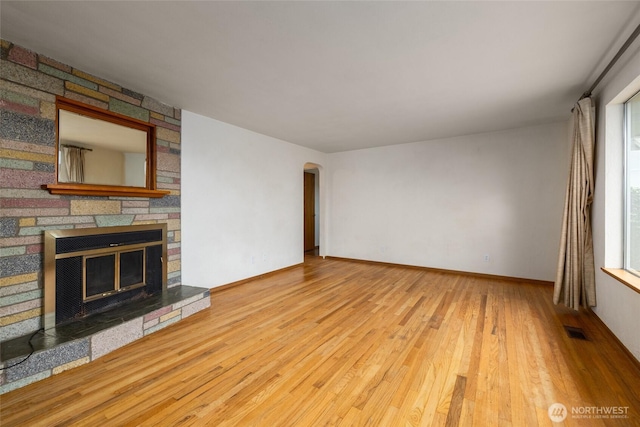 1411 38th St, Anacortes, WA 98221 - unfurnished living room with wood finished floors, a fireplace, arched walkways, and plenty of natural light