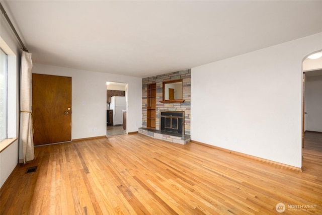1411 38th St, Anacortes, WA 98221 - unfurnished living room featuring wood finished floors, plenty of natural light, arched walkways, and a fireplace