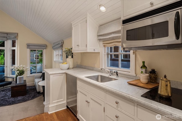 1617 Federal Ave E, Seattle, WA 98102 - kitchen with stainless steel microwave, black electric stovetop, white cabinetry, lofted ceiling, and dark wood-type flooring