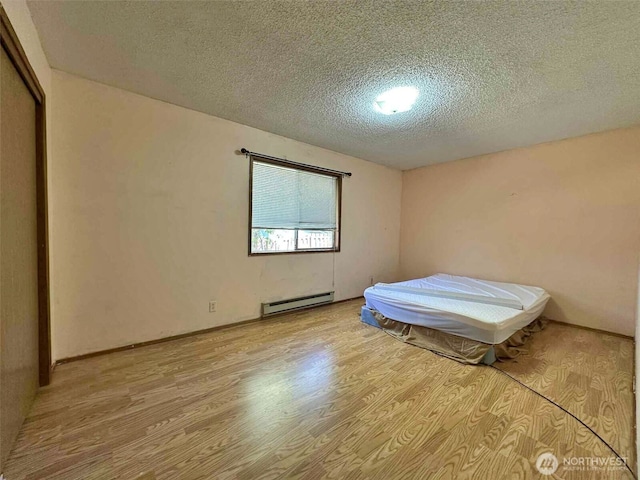798 Division Ave, Morton, WA 98356 - bedroom featuring a baseboard radiator, a textured ceiling, light wood-style floors, and a closet