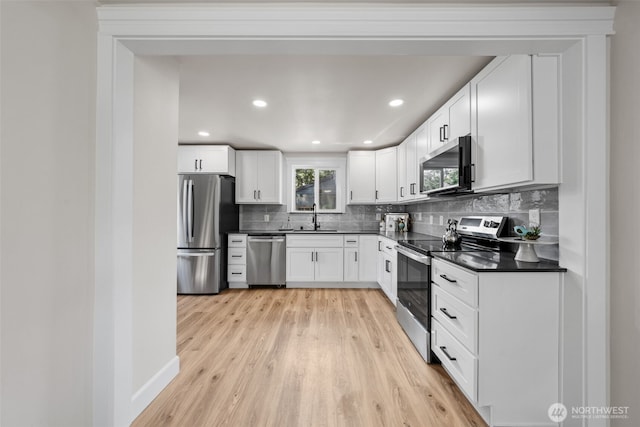 6416 S Huson St, Tacoma, WA 98409 - kitchen with stainless steel appliances, dark countertops, tasteful backsplash, light wood-style floors, and white cabinetry