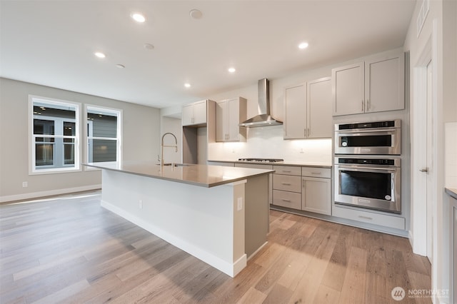 21725 SE 292 Nd Pl, Black Diamond, WA 98010 - kitchen with wall chimney exhaust hood, stainless steel double oven, gas stovetop, light wood-type flooring, and a center island with sink