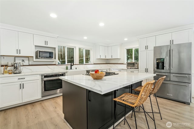 17519 33rd Ave NE, Lake Forest Park, WA 98155 - kitchen featuring stainless steel appliances, white cabinets, a kitchen island, a kitchen breakfast bar, and recessed lighting
