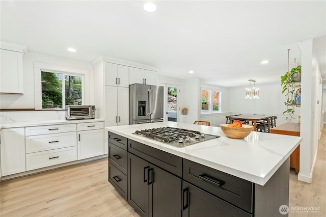17519 33rd Ave NE, Lake Forest Park, WA 98155 - kitchen with stainless steel appliances, white cabinets, light wood-style flooring, a chandelier, and a kitchen island