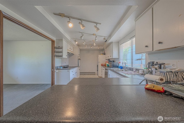 5735 NE 8th St, Renton, WA 98059 - kitchen with white cabinetry, track lighting, dark countertops, stainless steel appliances, and under cabinet range hood