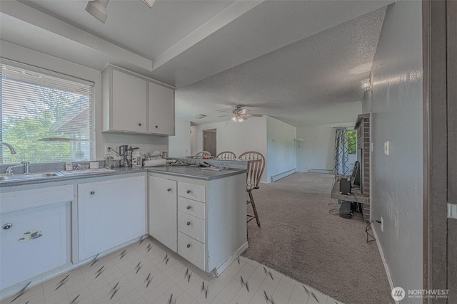 5735 NE 8th St, Renton, WA 98059 - kitchen with a peninsula, white cabinetry, ceiling fan, light carpet, and a textured ceiling