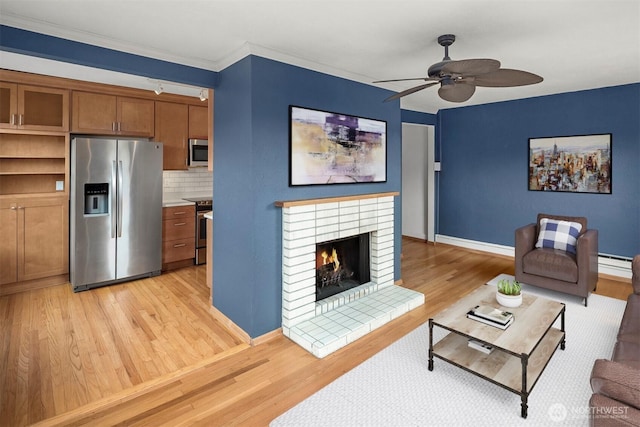 404 E Harrison St Unit 301, Seattle, WA 98102 - living room with light wood-style flooring, ceiling fan, a baseboard radiator, a brick fireplace, and crown molding