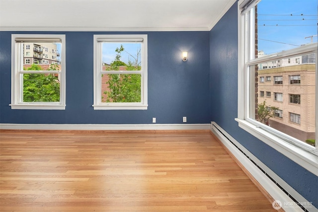 404 E Harrison St Unit 301, Seattle, WA 98102 - empty room with a baseboard radiator, light wood-style flooring, crown molding, and healthy amount of natural light